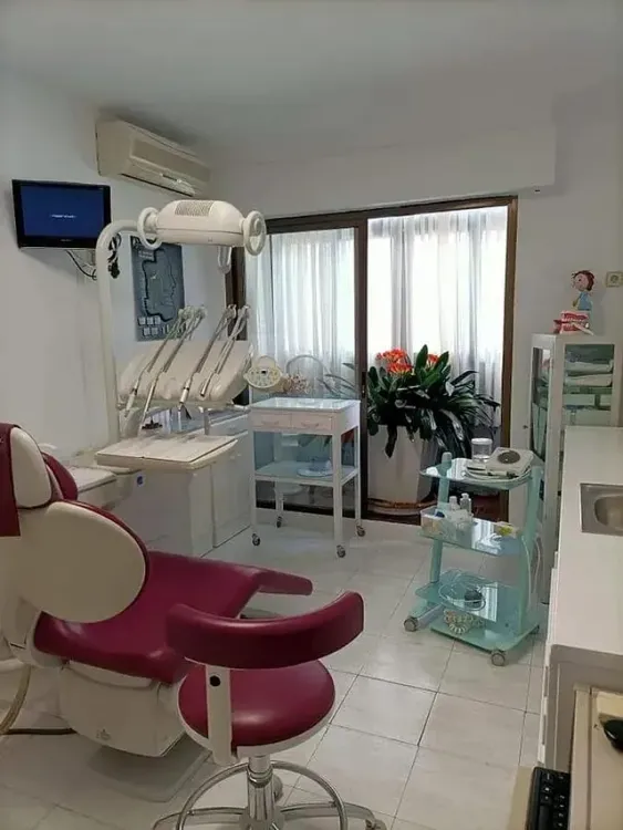 Un consultorio dental con sillón dental, lavabo y televisión.