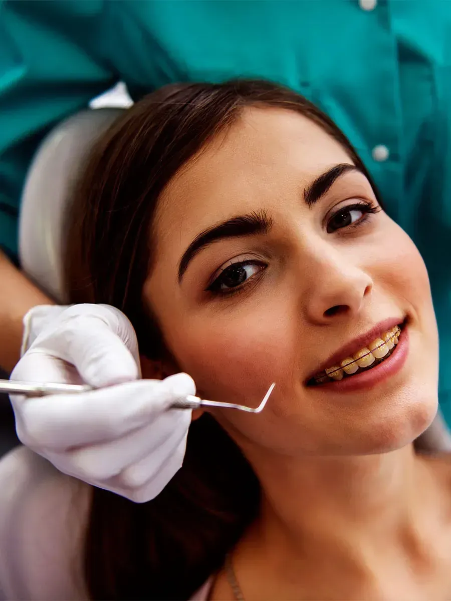 Una mujer con aparatos ortopédicos se hace examinar los dientes por un dentista.
