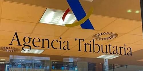 Letrero con la inscripción “Agencia Tributaria” en la fachada de un edificio de cristal.