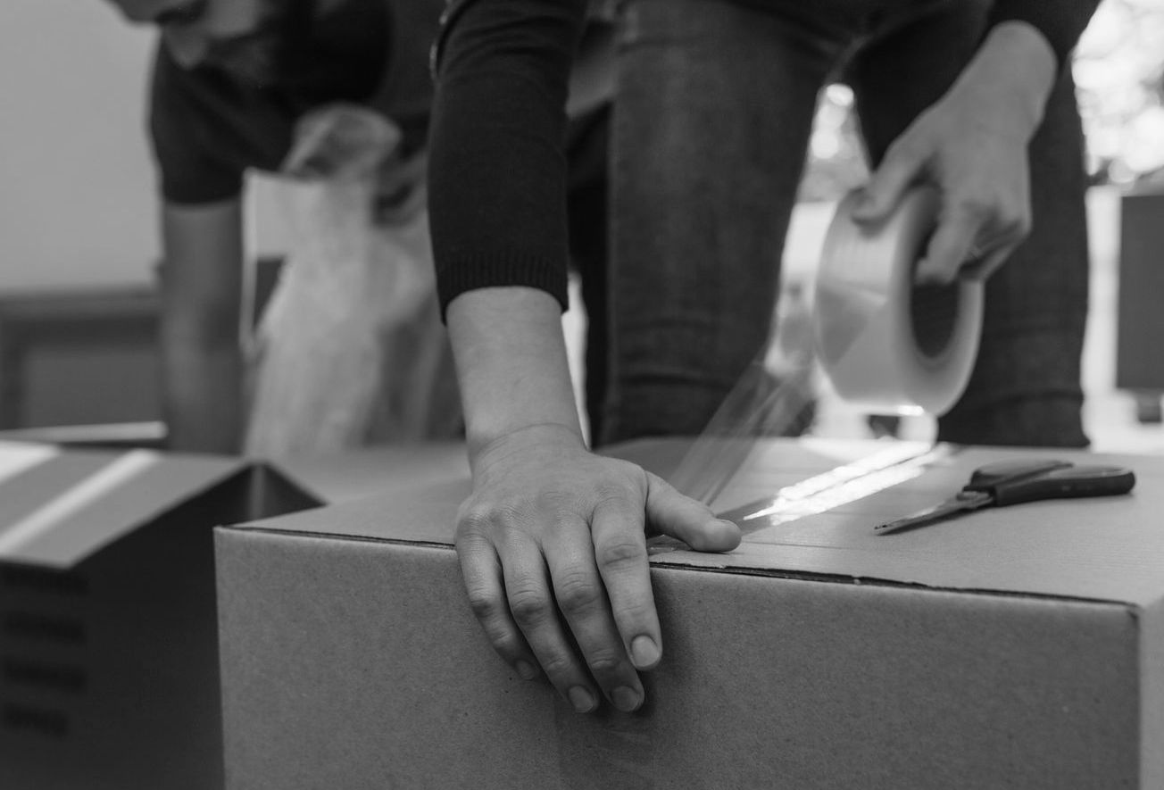 Un homme applique du Scotch sur un carton