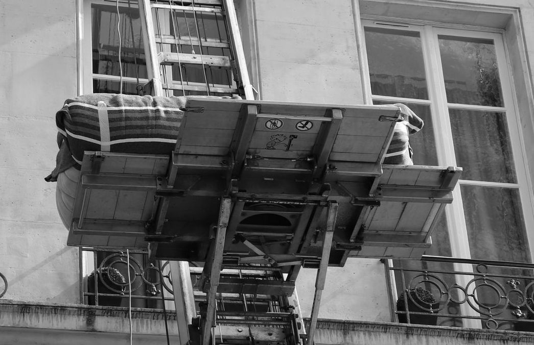 Un monte-meubles vu du dessous, un canapé posé sur la plateforme
