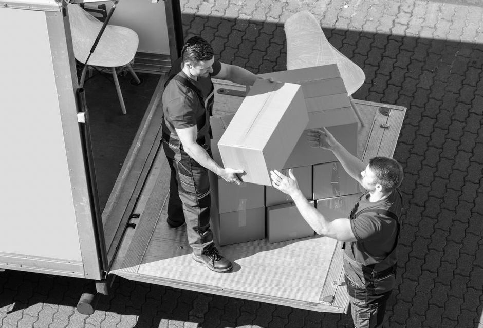 Deux déménageurs débarquent des cartons d'un camion