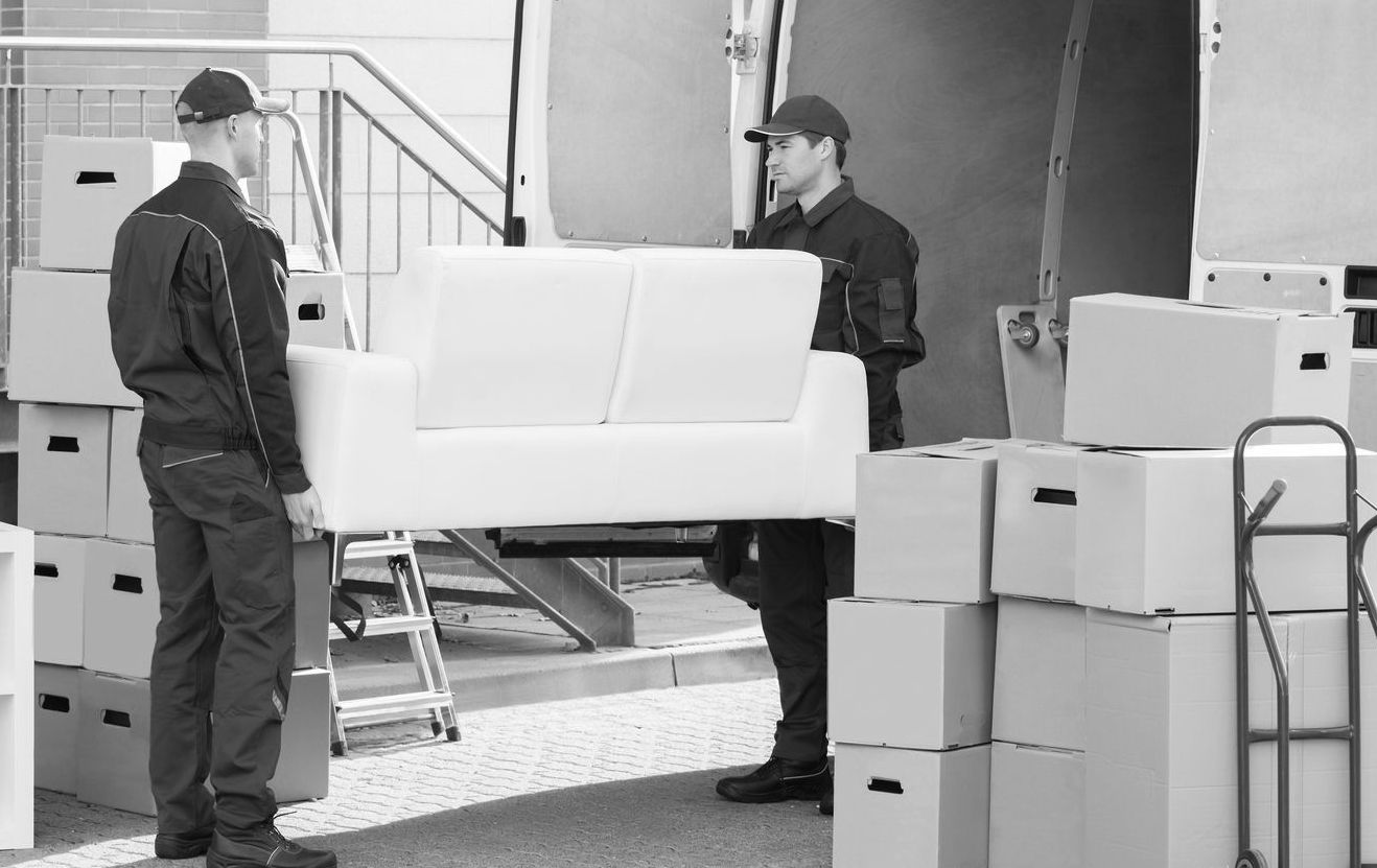 Deux déménageurs déchargent un canapé d'un camion