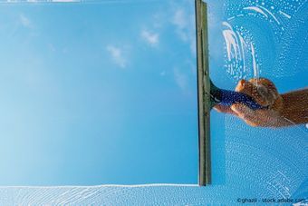 Hand und Scheibenwischer beim Fensterputzen ragen rechts ins Bild