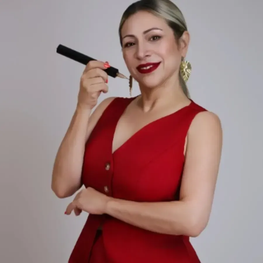 Mujer con un vestido rojo sosteniendo un tubo de lápiz labial rojo y sonriendo contra un fondo liso.