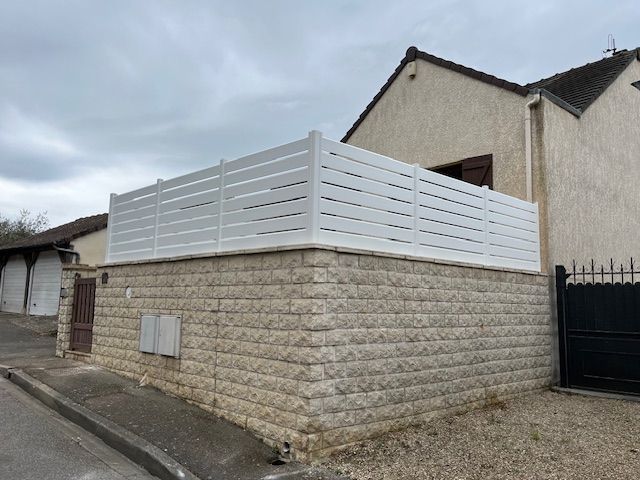 Vue d'angle d'un mur en pierre avec clôture en aluminium