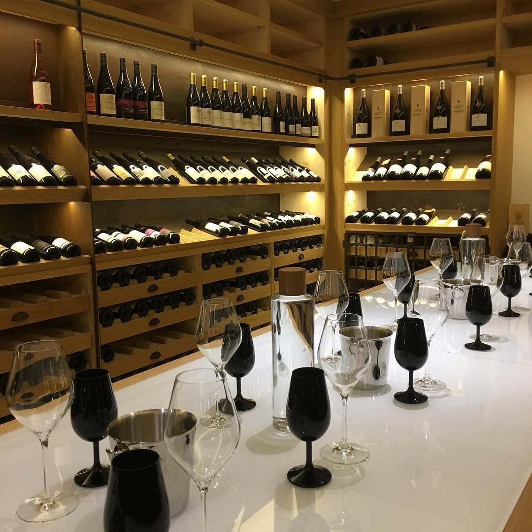 Élégante cave à vin avec des bouteilles sur des étagères en bois et des verres disposés sur une table de dégustation.