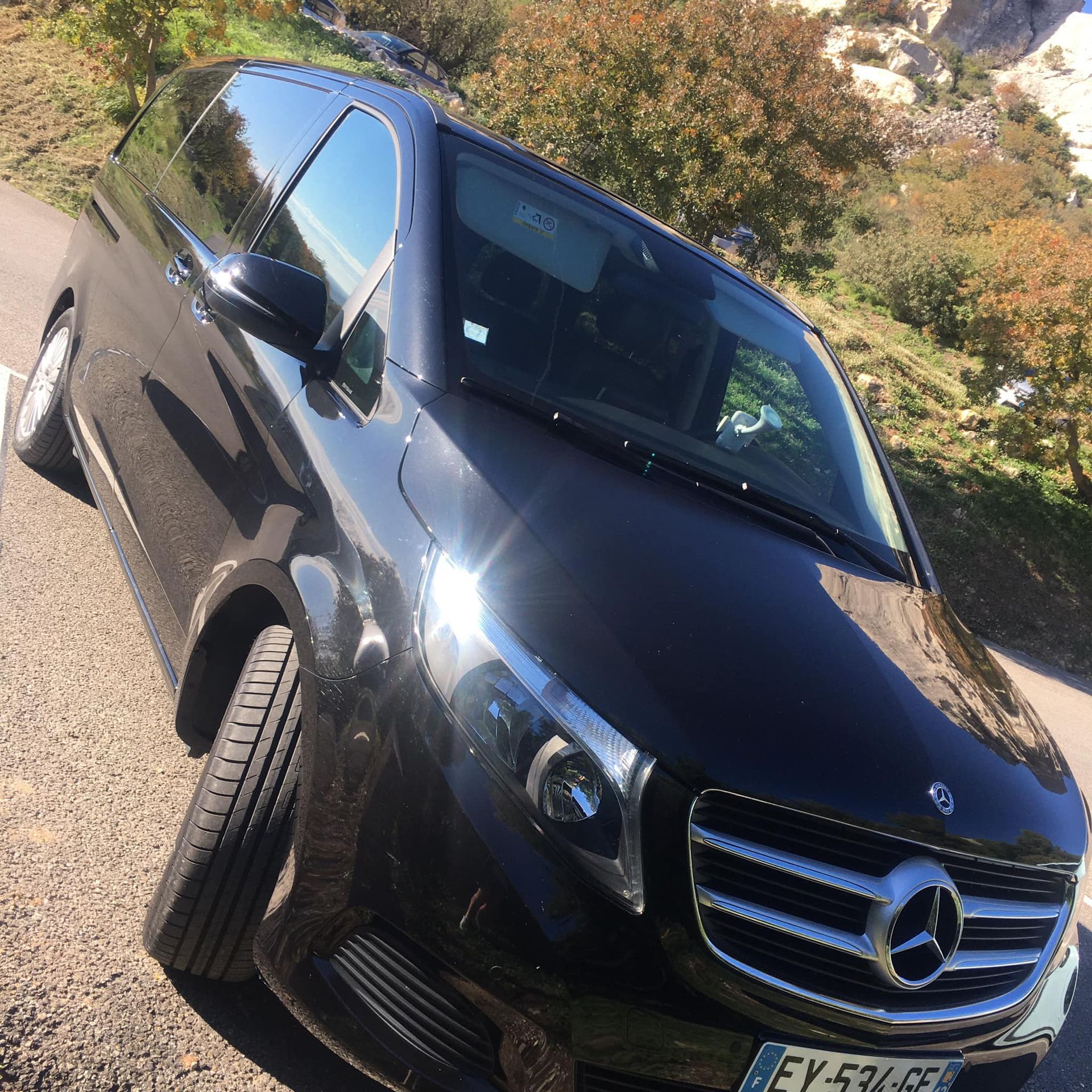 Un van Mercedes-Benz noir est garé en bord de route.