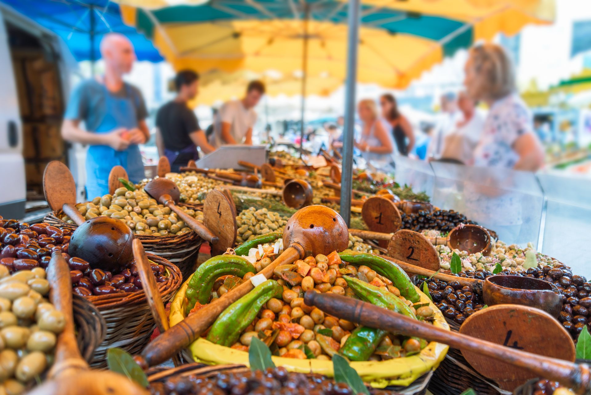 Étal de marché coloré avec des paniers de produits frais sous des parasols jaunes.