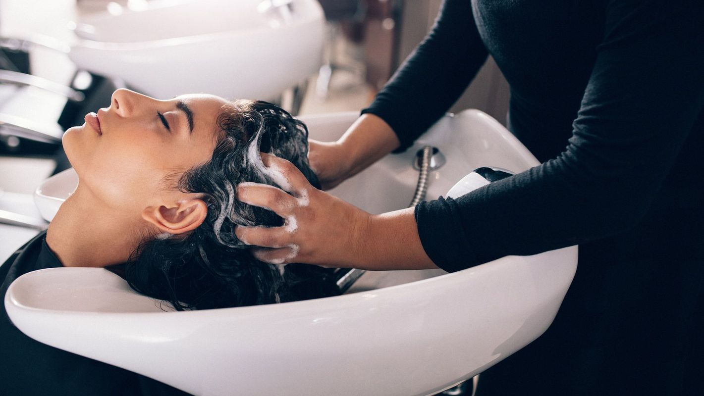 Une personne se fait laver les cheveux dans un salon de coiffure. Un professionnel lave et masse les cheveux du client.