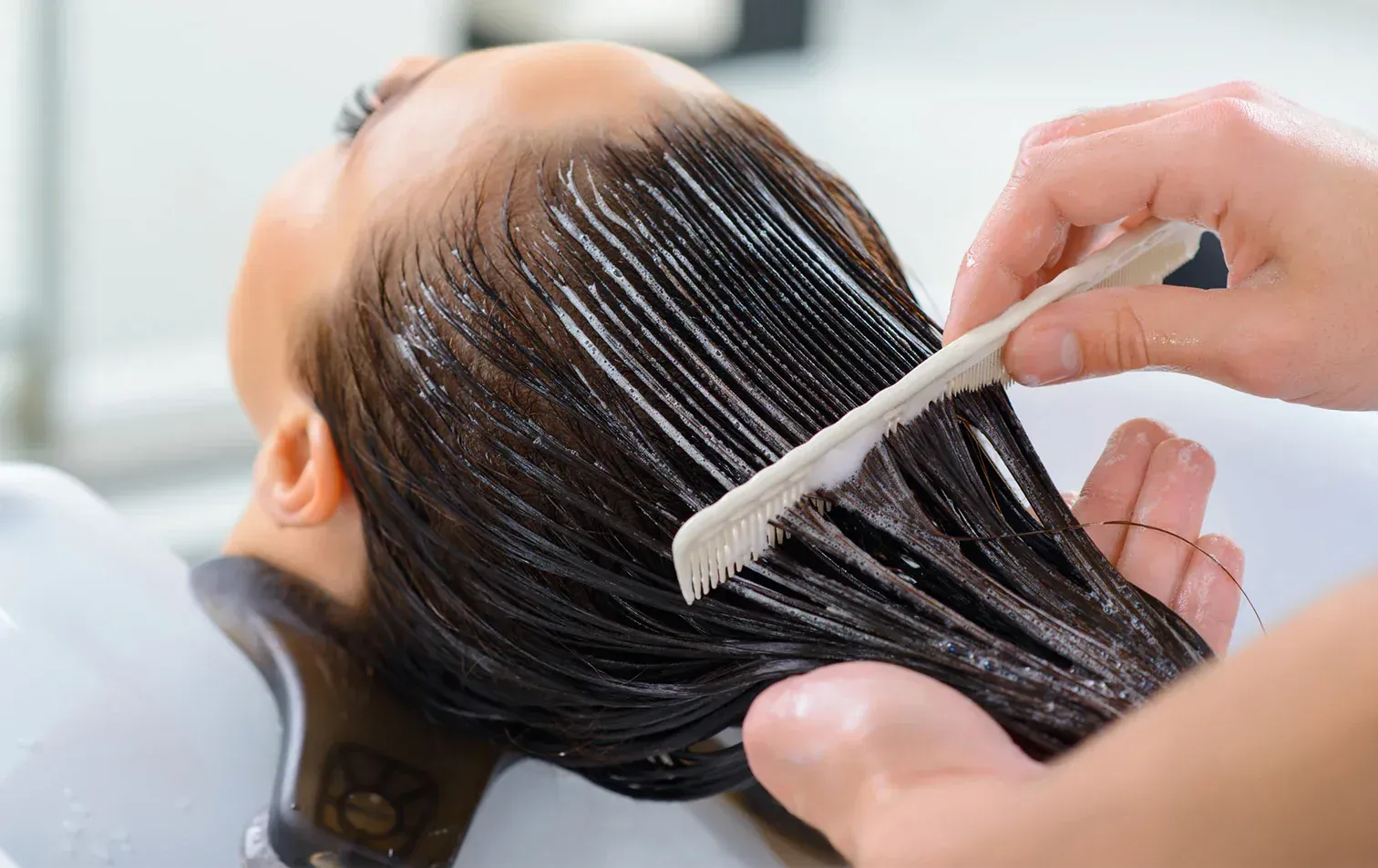 Les cheveux d'une personne sont peignés pendant l'application d'un soin capillaire.
