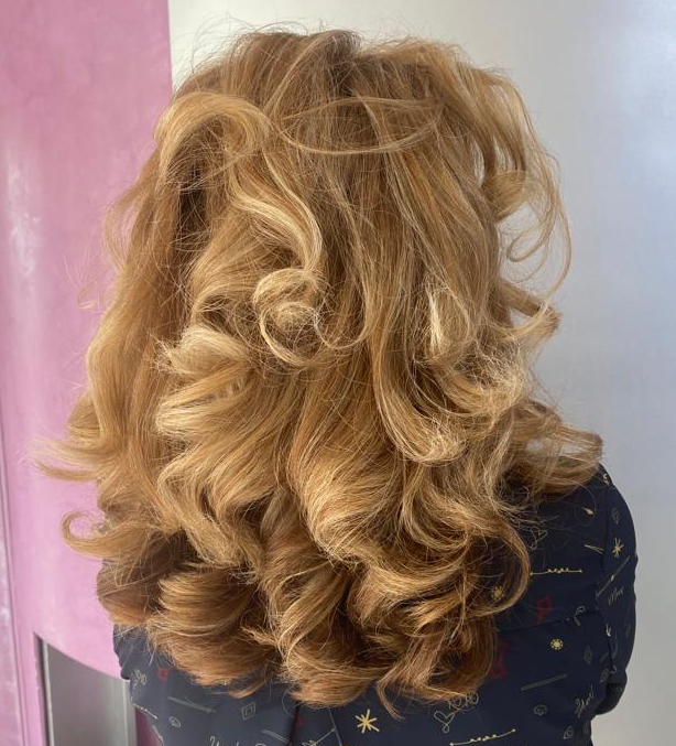 Une femme aux longs cheveux blonds, avec des boucles ou anglaises.