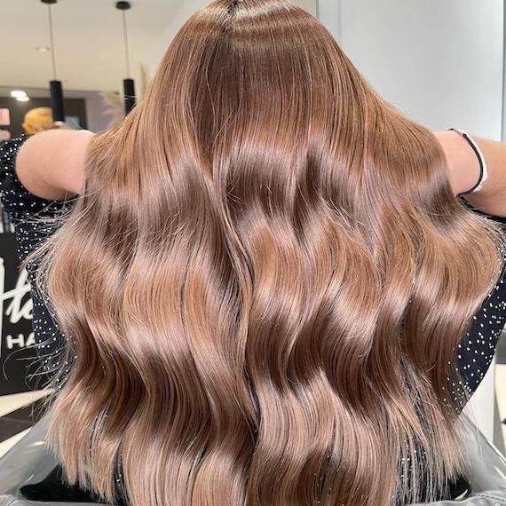 Femme aux longs cheveux ondulés châtain clair, coiffés en vagues souples.