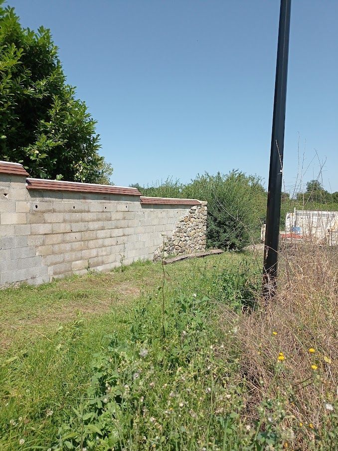 Mur de pierre claire patiné par le temps, sous un ciel d'un bleu limpide.