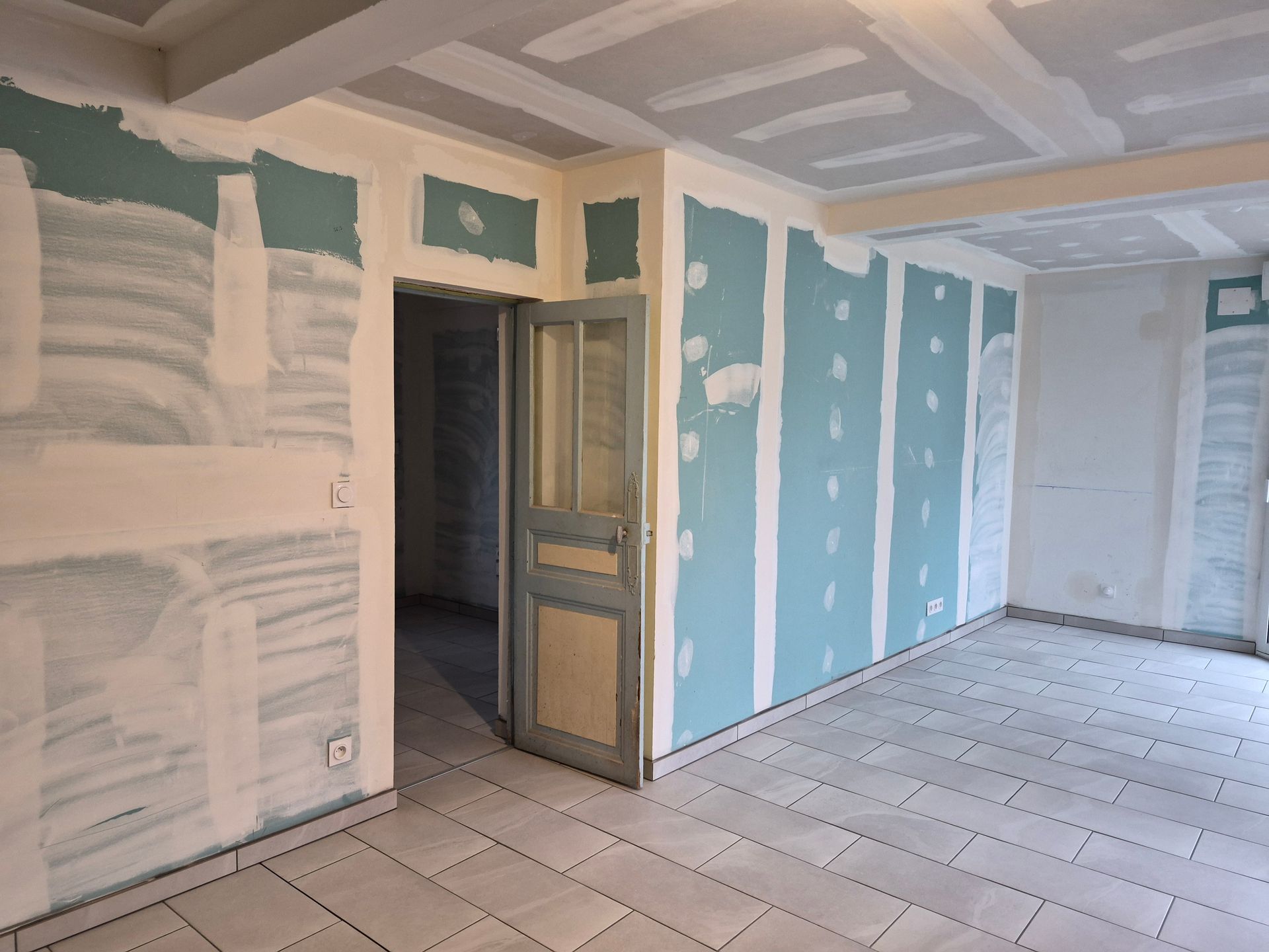 Une pièce en rénovation avec des cloisons sèches bleu turquoise, des joints de ruban adhésif.