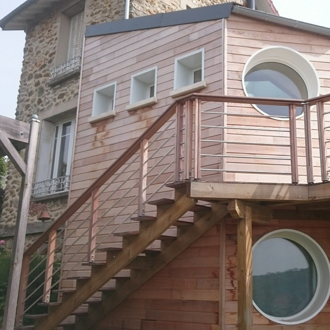 Une maison rustique en pierre avec une extension moderne revêtue de bois.
