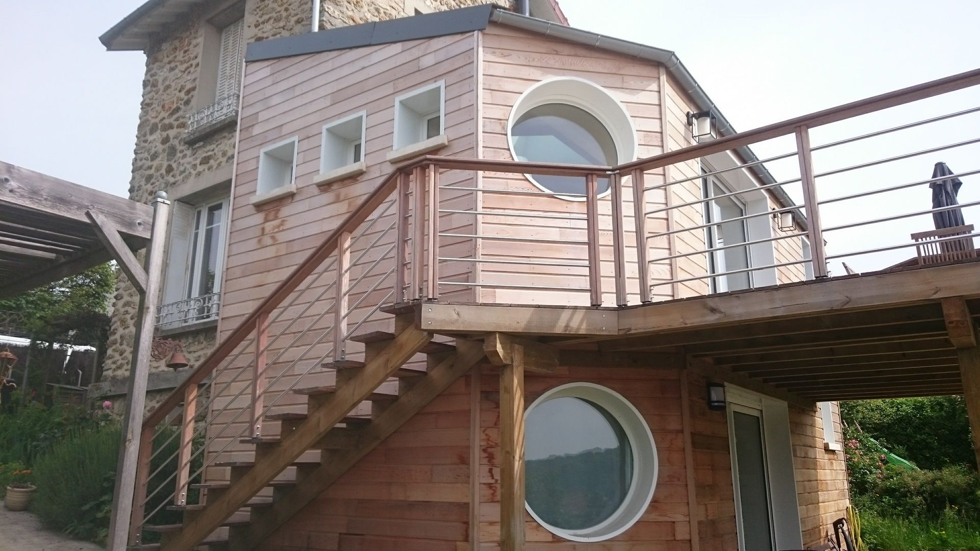 Maison en pierre avec une extension moderne en bois clair.
