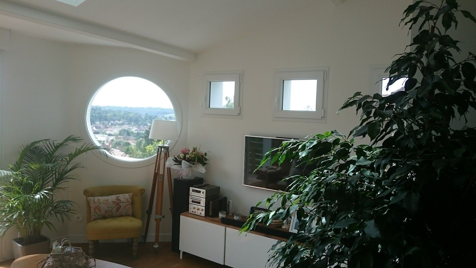 Un salon lumineux et moderne avec une grande fenêtre ronde.