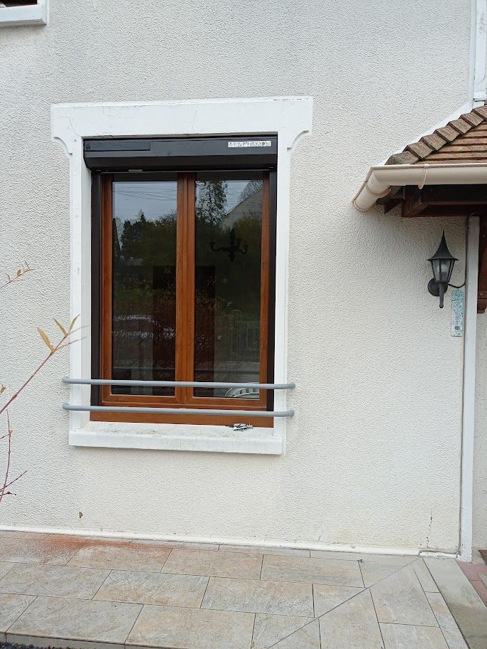 Une fenêtre à cadre en bois avec un volet roulant noir.