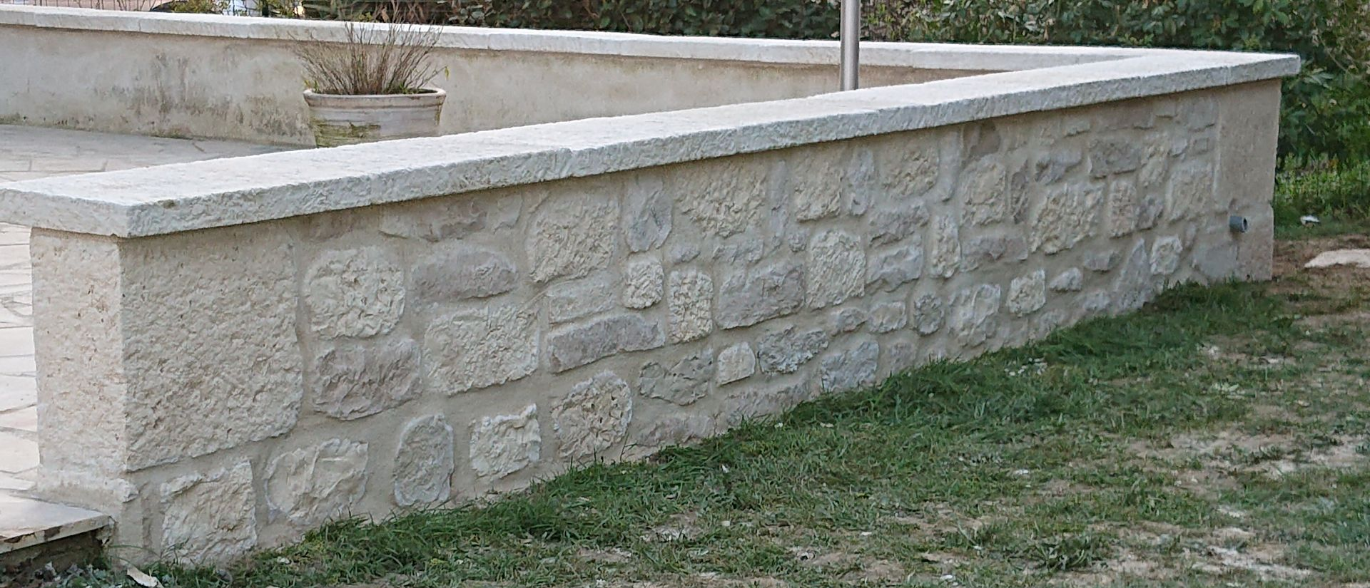Couverture et fenêtres de toit Mur de pierre avec un dessus en béton, construit près de l'herbe.