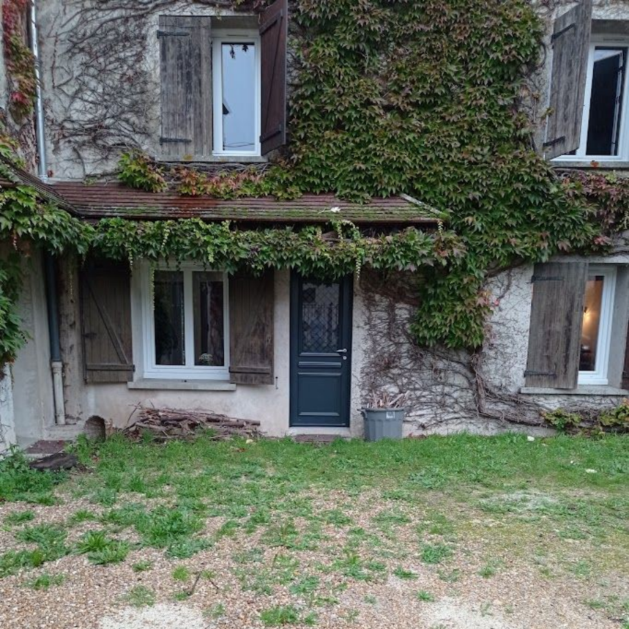 Une porte vert foncé avec un heurtoir argenté et une fenêtre assortie.