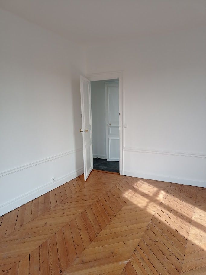 Un salon moderne avec un canapé gris, une table à manger blanche, des suspensions en osier.