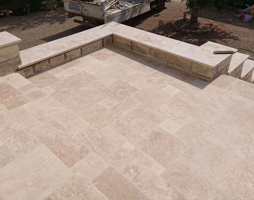 Marches et palier en pierre avec carrelage beige clair et muret.