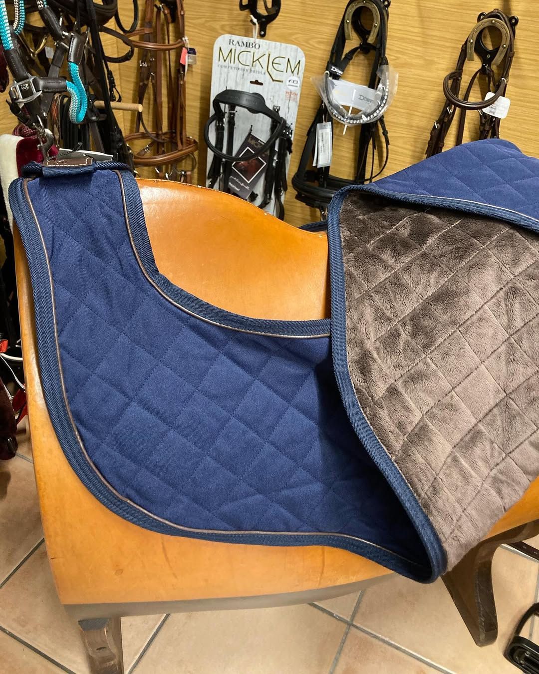 Un tapis de selle bleu et marron est posé sur une chaise en bois