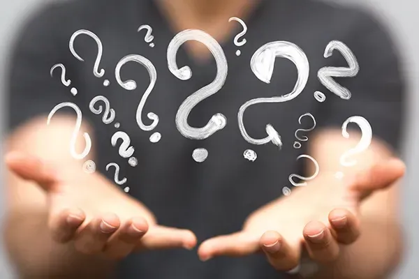 Die Hände sind zu einer Schale geformt und halten leuchtend weiße Fragezeichen.