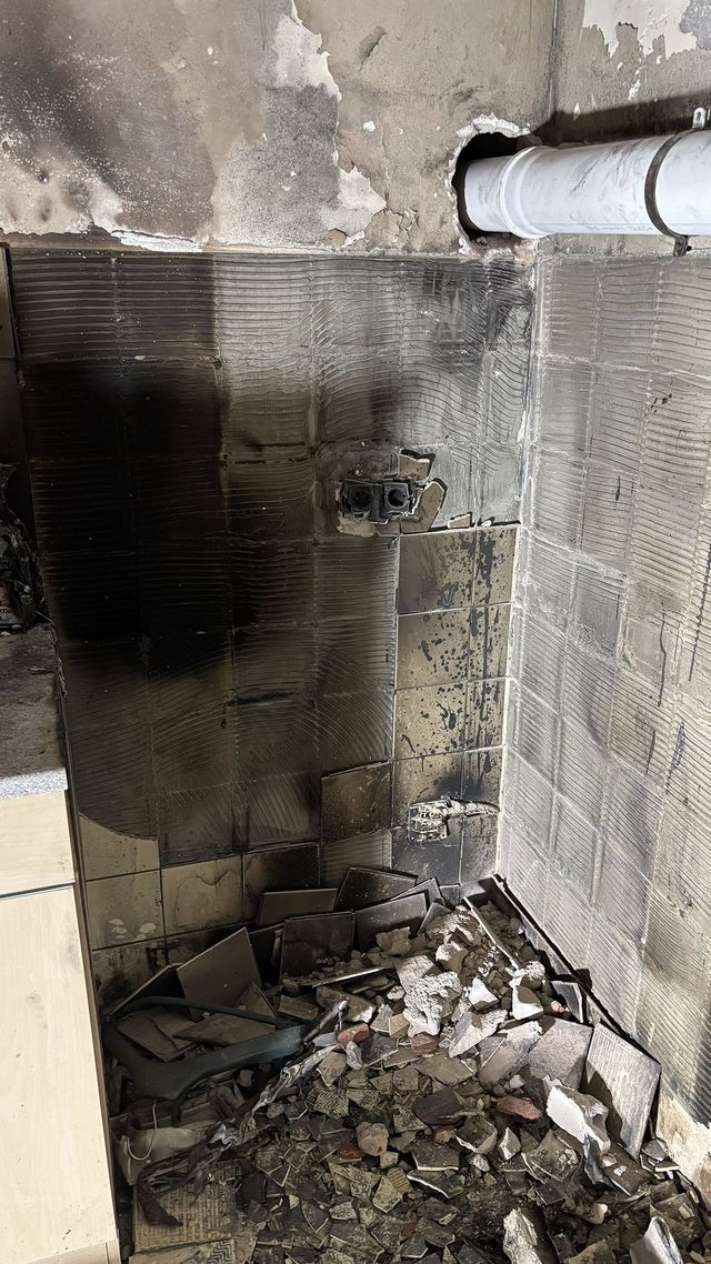 Ausgebranntes Zimmerinneres mit Jacken, Nivea-Creme-Aufdruck und Schutt. Rauch und Ruß bedecken die Oberflächen.