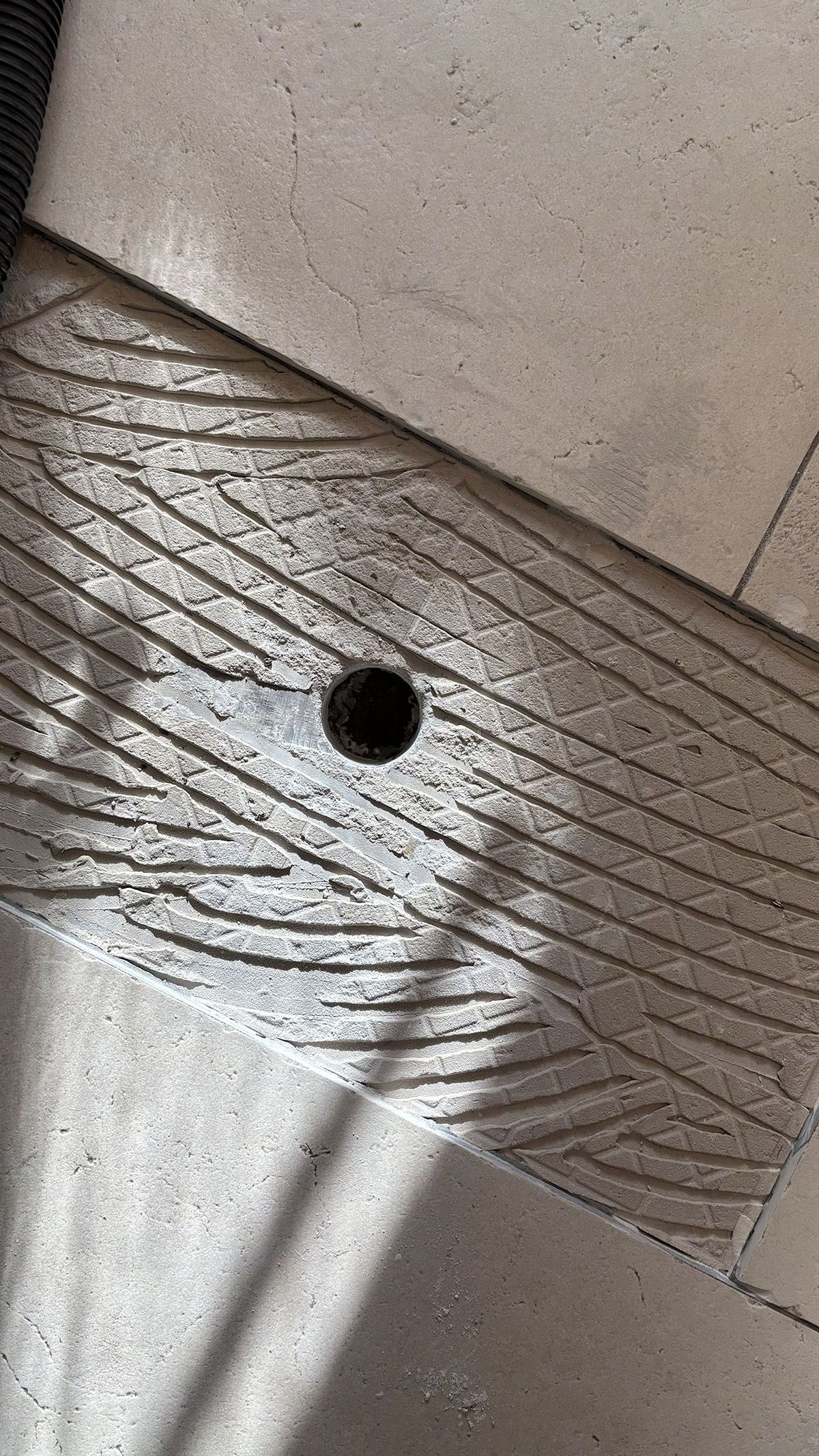 Nahaufnahme eines Holzbalkens mit einem dunklen Loch darin, der auf einer Betonoberfläche ruht.