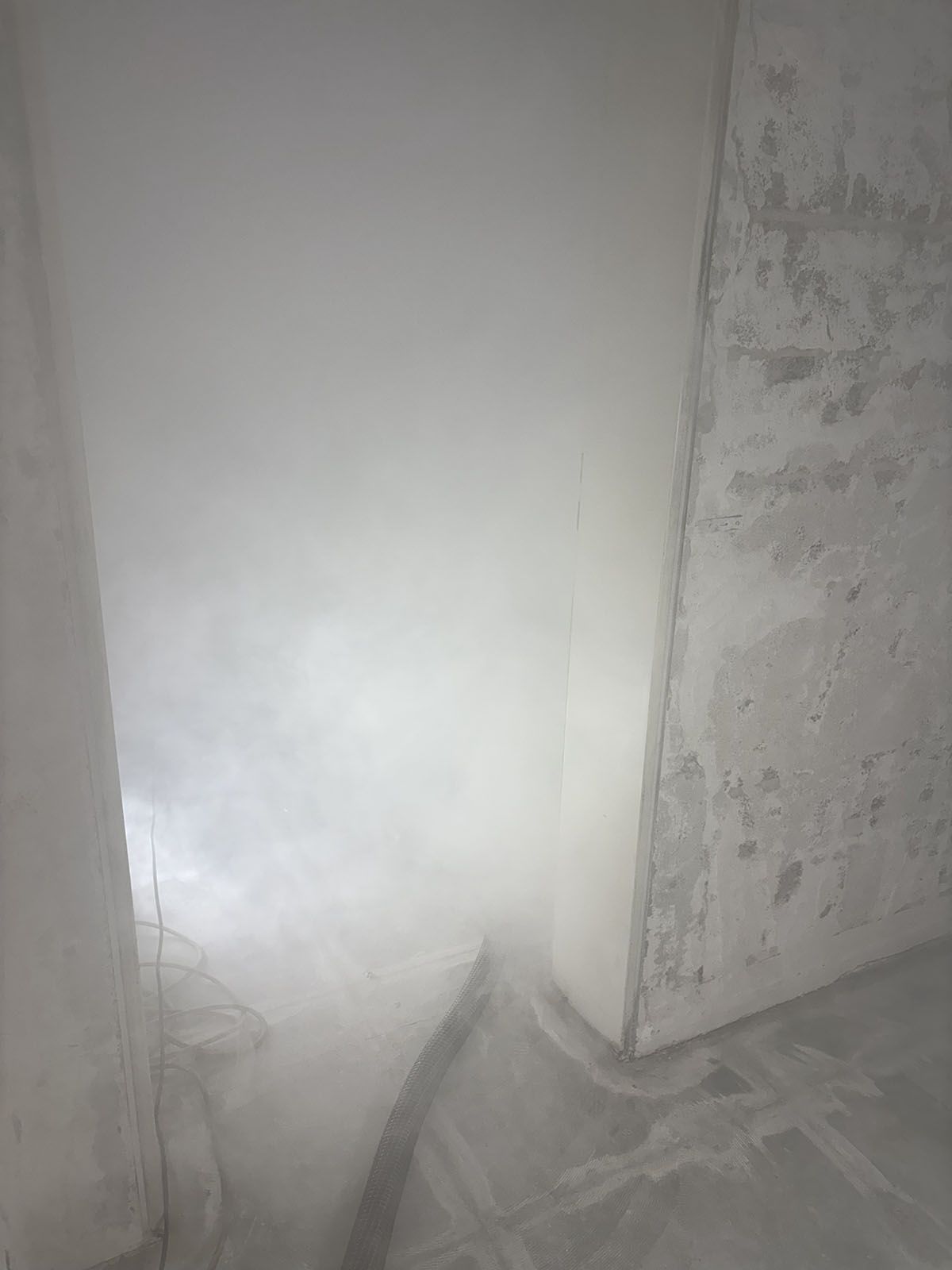 Weiß gestrichene Deckenecke, unfertige Betonwand, Winkelansicht.