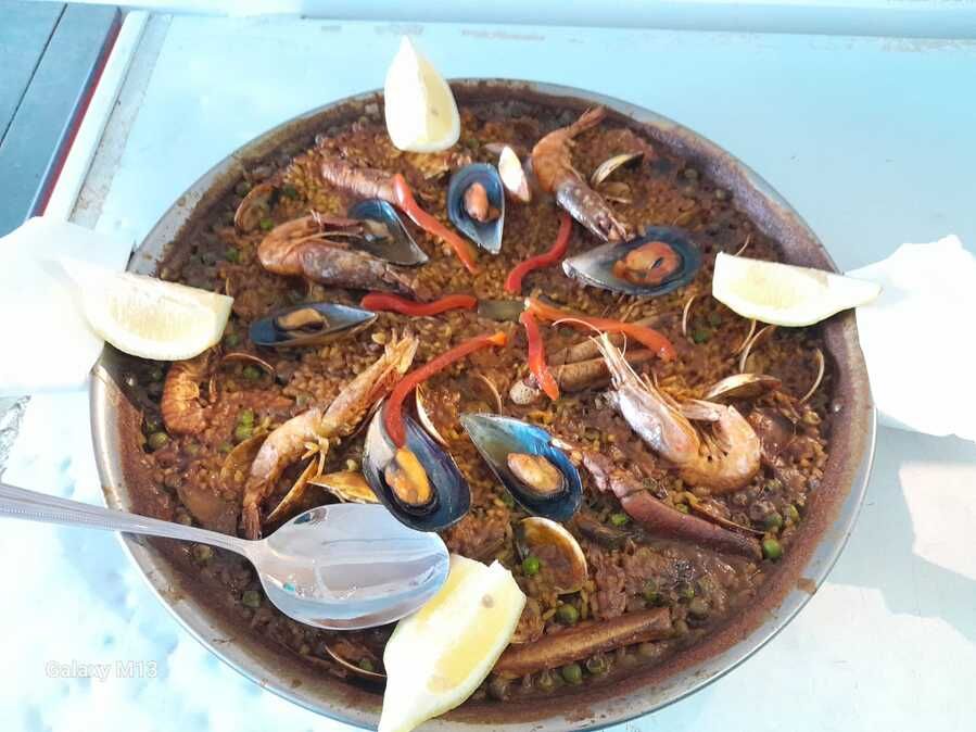 Una sartén de paella de mariscos con una cuchara dentro