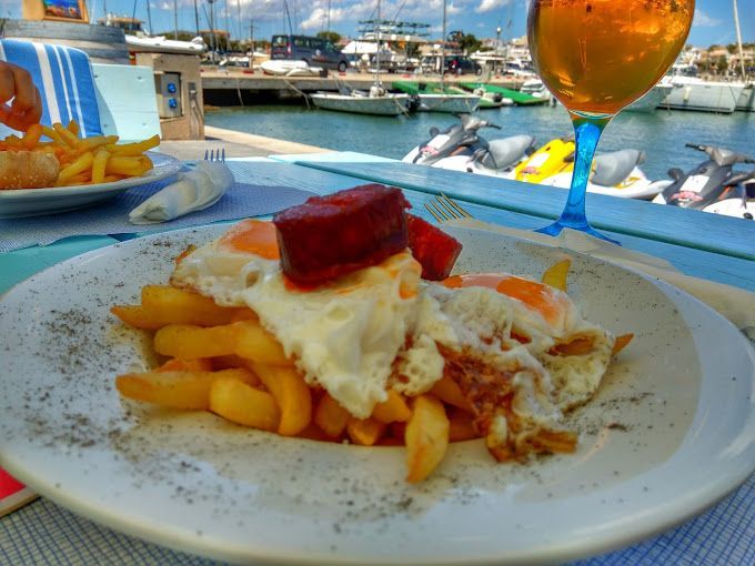 Un plato de comida con huevos y papas fritas junto a un vaso de cerveza.