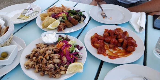 Una persona está sentada en una mesa con platos de comida sobre ella.