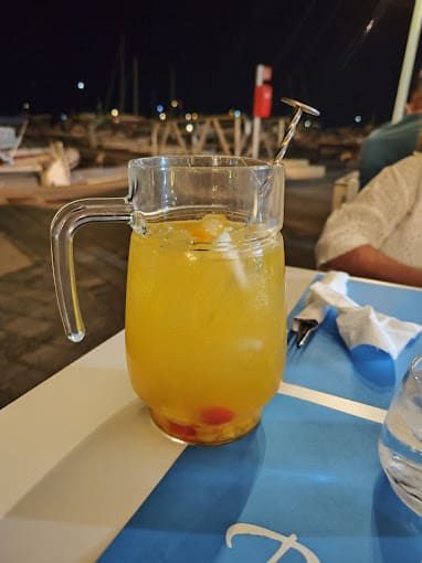 Una jarra de jugo de naranja con una pajita sobre una mesa.