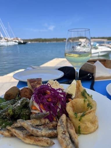 Hay un plato de comida y una copa de vino en la mesa.