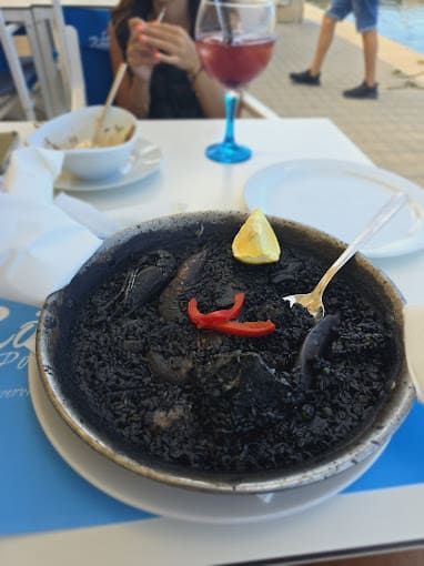 Un plato de arroz negro con una cuchara dentro.