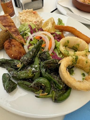 Un plato blanco cubierto con una variedad de alimentos sobre una mesa.