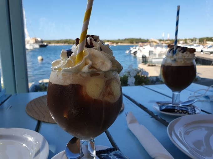 Un vaso de helado con crema batida y una pajita