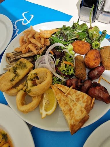 Un plato blanco cubierto con una variedad de alimentos sobre una mesa.
