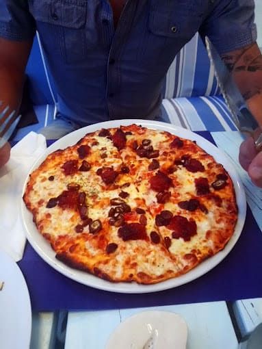 Una pizza con pepperoni y queso en un plato blanco