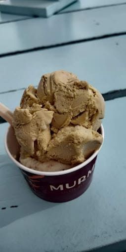 Una taza de helado con una cuchara dentro está sobre una mesa.