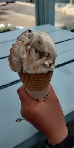 Una persona sostiene un cono de helado en su mano.