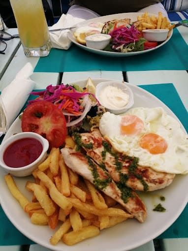 Un plato de comida con pollo, huevos, papas fritas y una ensalada en una mesa.