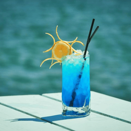 Una bebida azul con una pajita y una rodaja de limón.