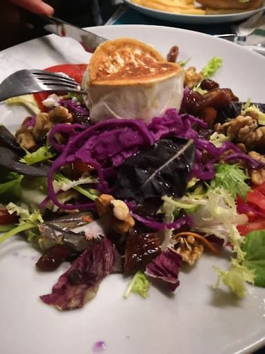 Una ensalada con un trozo de queso de cabra encima