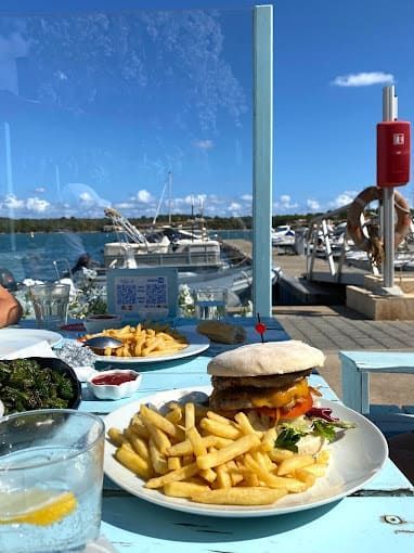 Un plato de comida con una hamburguesa y papas fritas en una mesa.