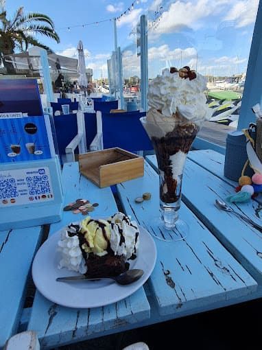 Un plato de comida y un vaso de helado sobre una mesa.