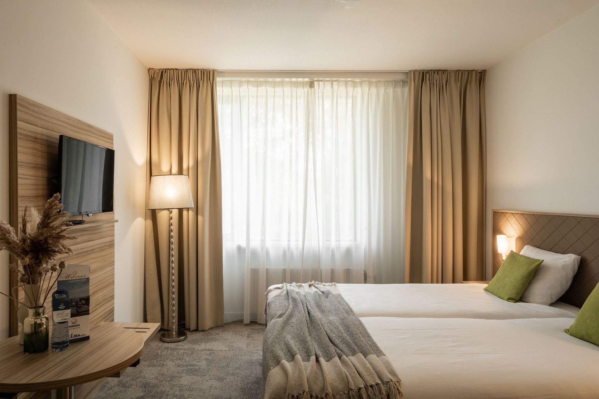 Een hotelkamer met twee bedden en een flatscreen-tv.